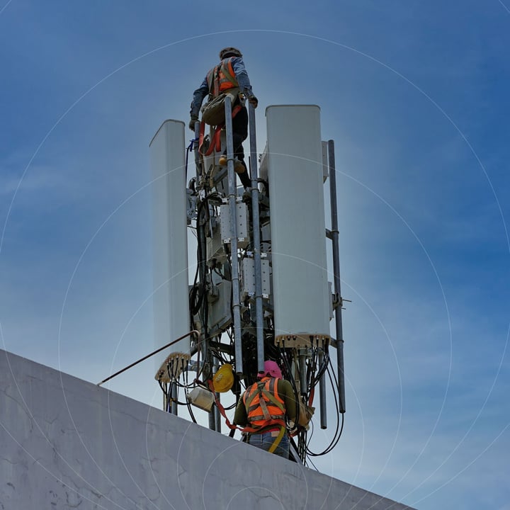 Engineers upgrading a telecom tower - representing 2G network shutdown and LTE-M migration.