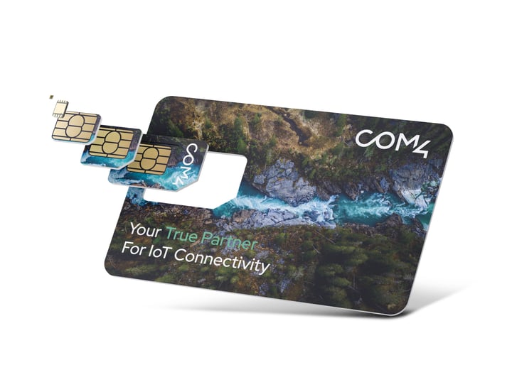 Com4 SIM card in three sizes (standard, micro, nano) fanned out beside a COM4-branded card featuring an aerial forest photo and the tagline 'Your True Partner For IoT Connectivity.