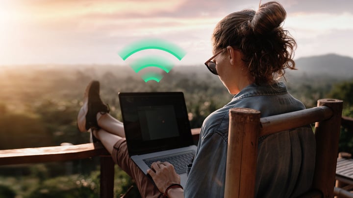Woman using laptop outdoors with Wi-Fi icon - symbolizing Fixed Wireless Access (FWA) connectivity