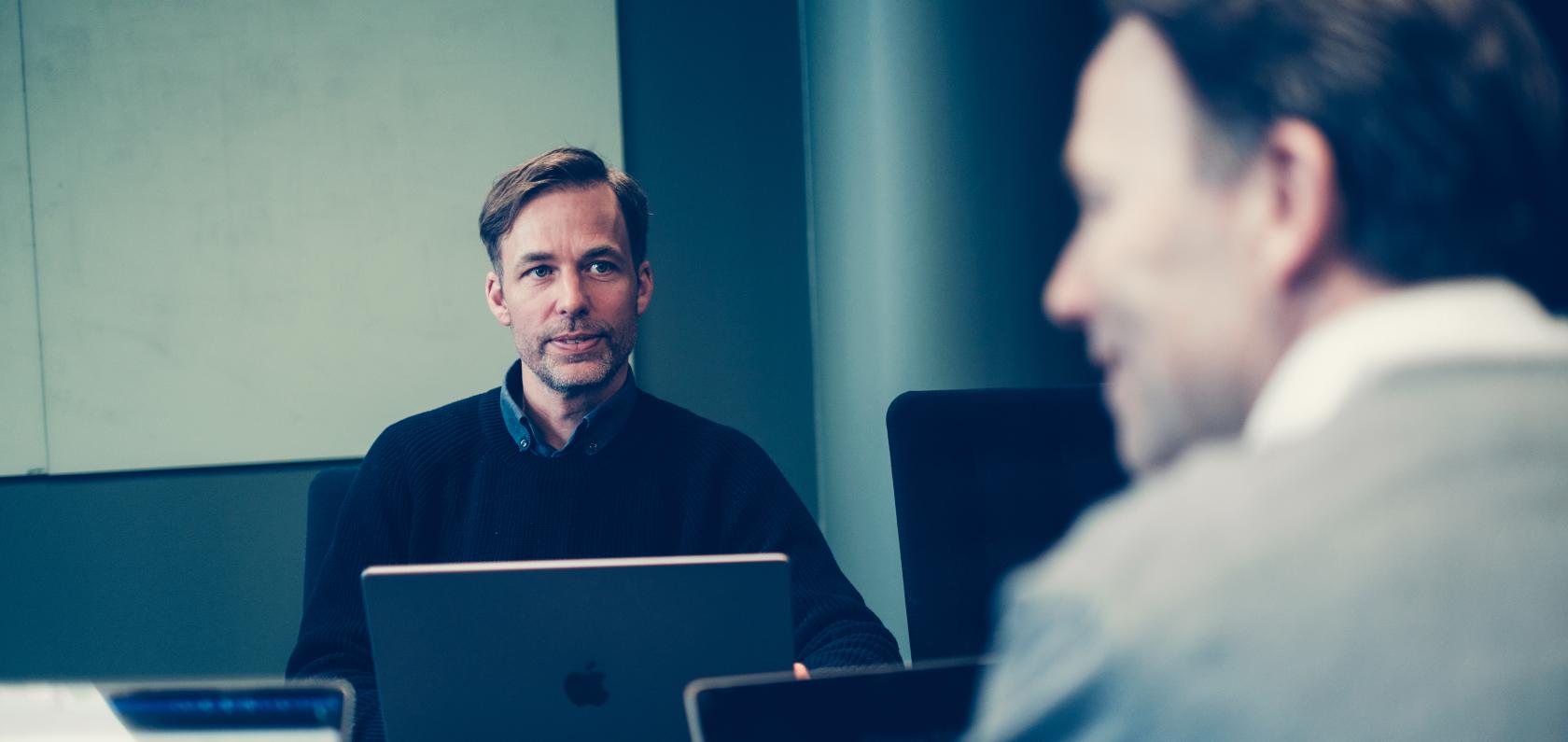 Two Com4 colleagues in conversation over a table representing the leadership team