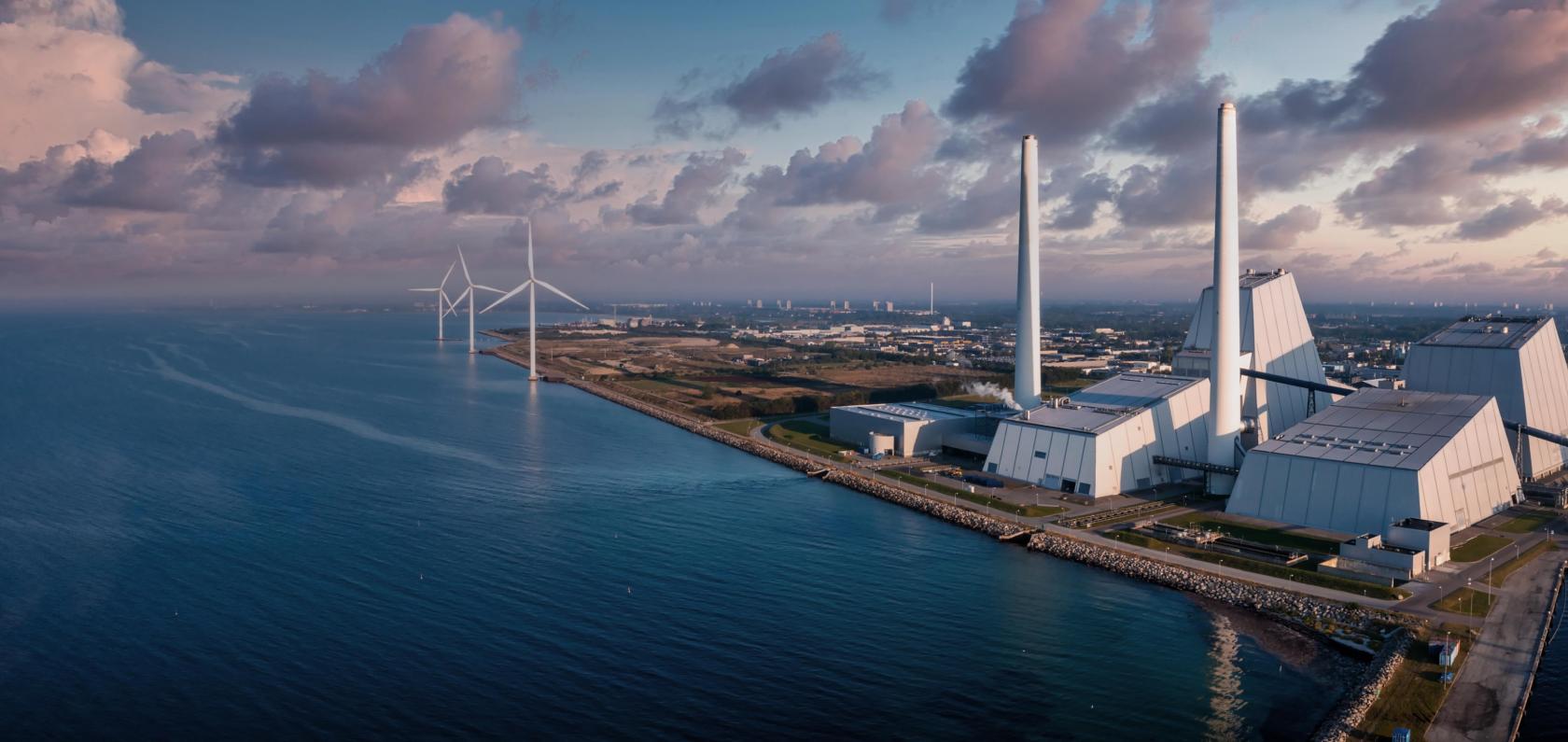 Industrial facility with wind turbines on the horizon representing energy and utilities