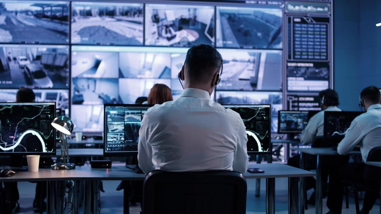 Man with headset infront of screens working on IoT Security
