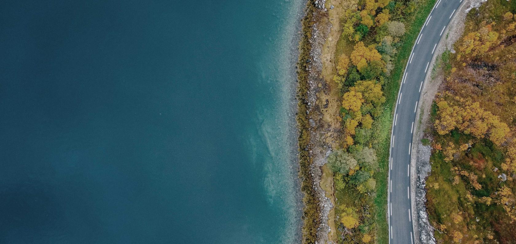 Aerial view of a coastal road representing the Com4 journey and Norwegian roots