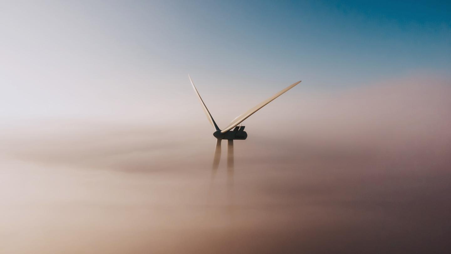 Wind turbines against a cloudy sky representing sustainable IoT-connected industries