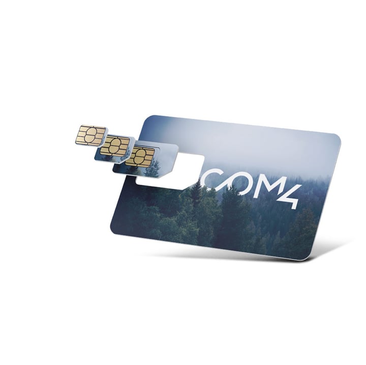 A Com4 SIM card with a forest and misty sky design, shown with three nested SIM sizes (standard, micro, nano) partially ejected from the card, set against a white background.