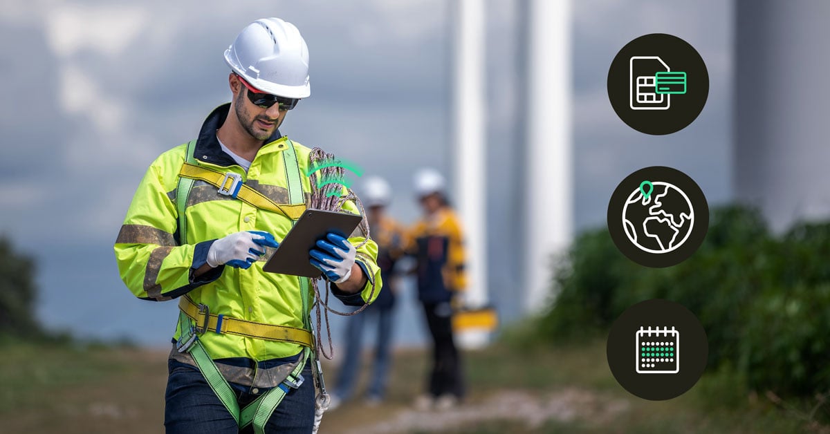 Wind turbine technician in safety gear and harness checking a tablet on-site, with colleagues and turbines in the background, alongside icons for IoT SIM connectivity, global coverage, and scheduled maintenance.