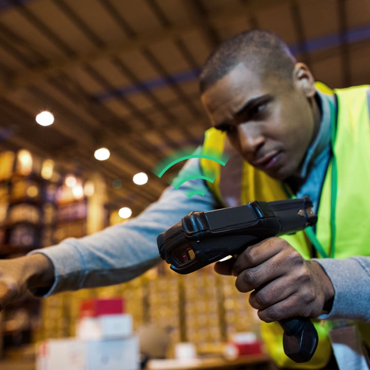 Worker in warehouse using IoT connectivity to manage inventory and logistics processes