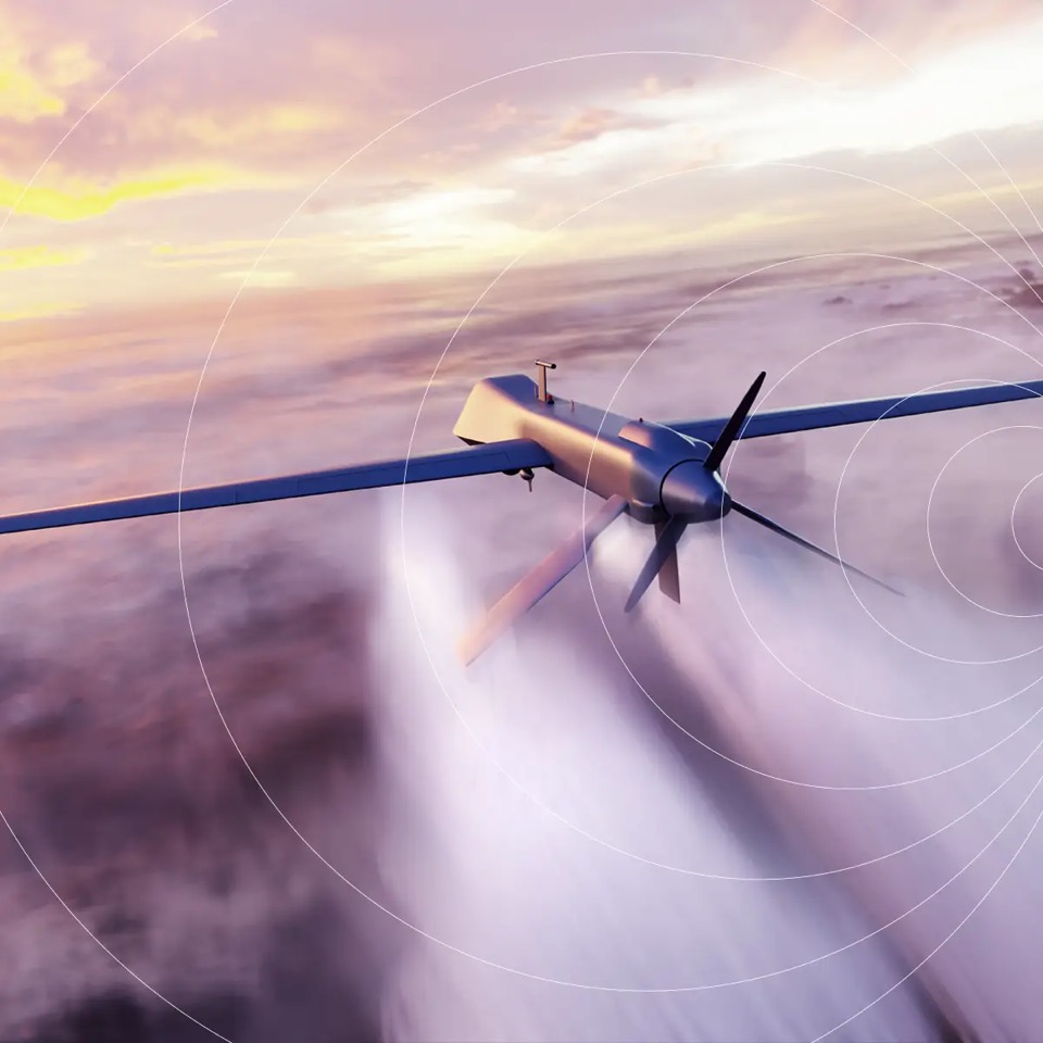 En militær overvåkningsdrone som flyr ved solnedgang med signalringer for IoT-tilkobling, og som illustrerer sikre trådløse nettverk for forsvarsoperasjoner.